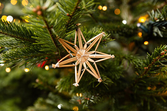 &Eacute;toile artisanale en paille suspendue au sapin de No&euml;l avec guirlande lumineuse en bokeh
