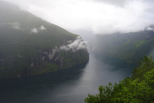 Misty Geirangerfjord with dramatic cliffs and waterfalls in Norway