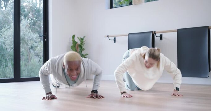 Diverse pair doing push-ups in studio, glance sparking speed, high-five, man rising, woman kneeling