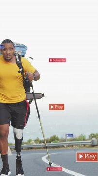 Animation of social media icons over african american man with prosthetic leg trekking on the road