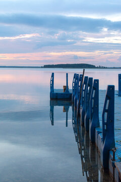 Blue plastic floating pier on a calm lake at sunset