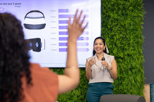 Diverse female coworkers presenting VR headset data in meeting room with microphone, copy space