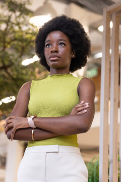 Adult woman standing confidently with arms crossed in modern office wearing lime-green top