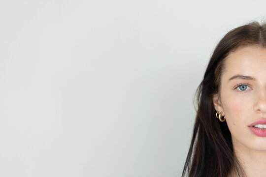 Holding gaze at camera, adult female wearing dark top, gold hoop earrings in studio, copy space