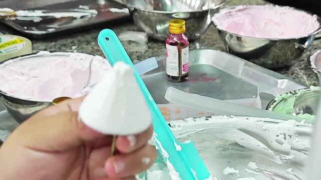 Using a metal spatula to scrape white cake cream frosting.