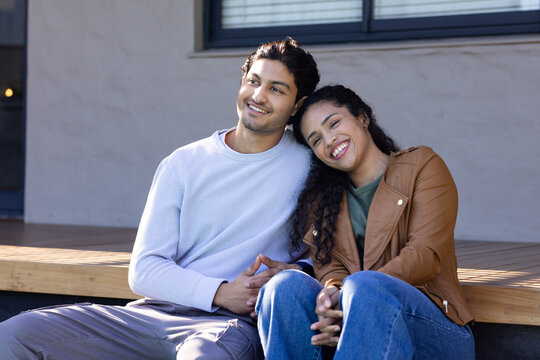 African American couple sitting on porch step, woman leaning on shoulder, window blinds visible