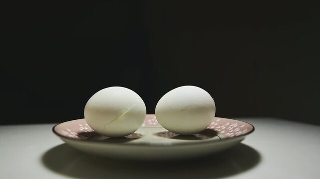 Changing Light and Shadows on White Eggs Against a Black Background