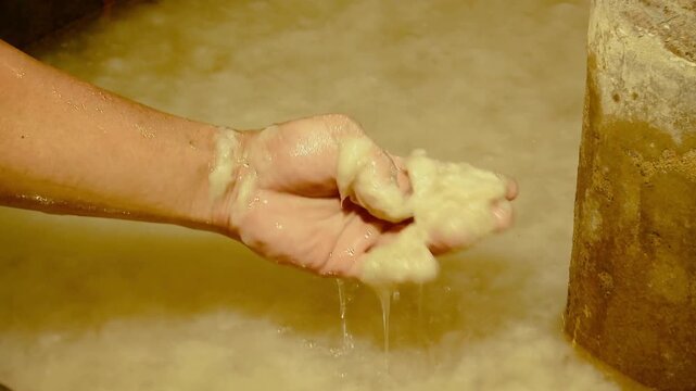 Hand taking out paper pulp out of tank in paper mill workplace close up.