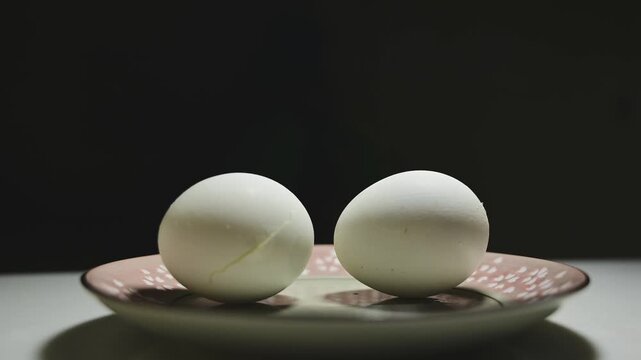 Changing Light and Shadows on White Eggs Against a Black Background