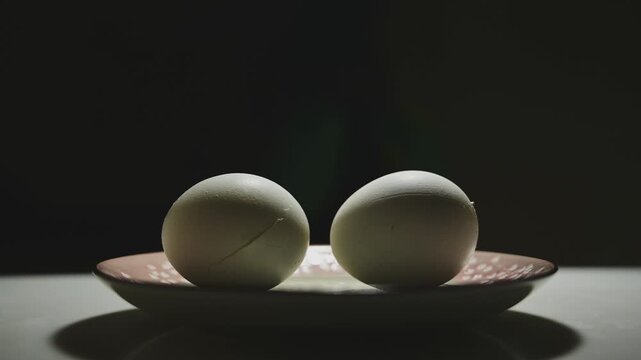 Changing Light and Shadows on White Eggs Against a Black Background