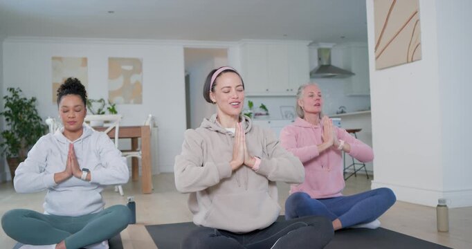 Diverse women in hoodies on yoga mats at home following center woman guiding breath seeking calm