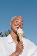 Obraz premium Joyful woman eating ice cream cone outdoors against blue sky for summer lifestyle banner and social media background use