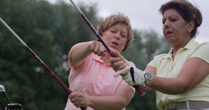 Golf course, trainer teaching woman and club in field, nature or outdoor for help in lesson. Golfers, coach and person learning to hold driver grip, healthy exercise or talking, training and sports
