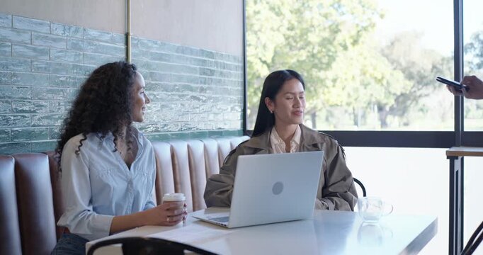 Diverse women coworkers, server presenting card reader, tapping and reviewing laptop print at cafe