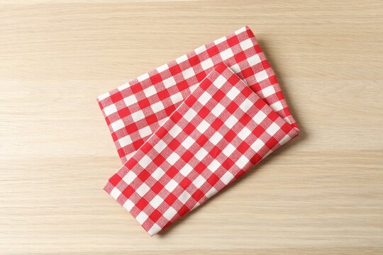 Red checkered napkin on wooden background, top view