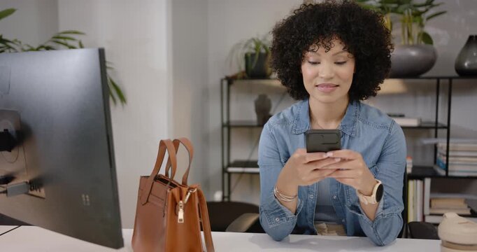 African American woman replying to phone alert, scrolling and answering call, smiling at desk