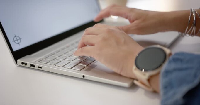 Hands are lifting from rest and starting light keystrokes on silver laptop, completing work on desk