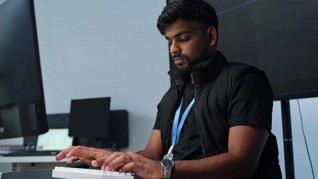 Concentrated software developer writing code at a workstation surrounded by several computer screens in a contemporary office