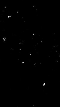 Large Particles Flickering in Stop Motion on Black.
White fragments flash in discrete stop-motion steps across a deep black background. Grain texture overlay with particles, noise effects.