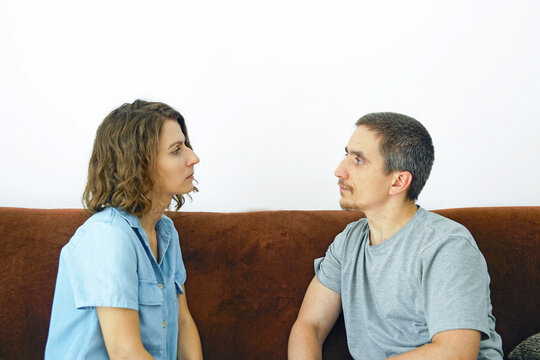 Сouple facing each other with serious expressions during tense conversation. Depicts relationship confrontation, difficult partner dialogue, and relationship problems requiring honest communication.