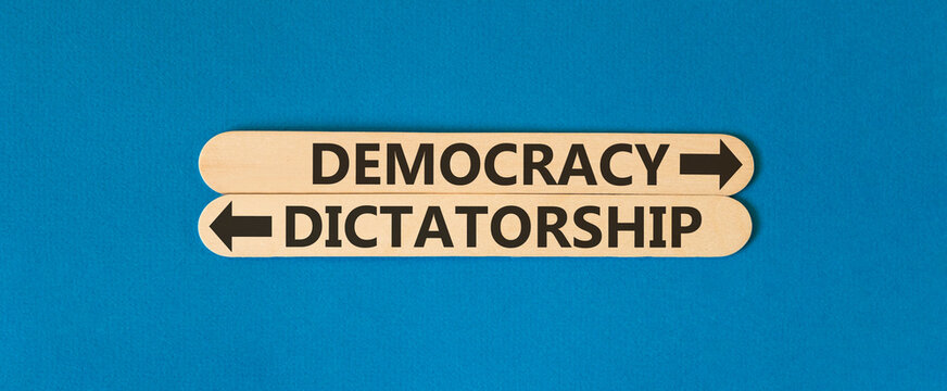 Democracy or dictatorship words symbol. Concept words Democracy Dictatorship on beautiful wooden sticks. Beautiful blue background. Business democracy dictatorship concept. Copy space
