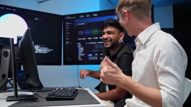 Two software developers working together in a contemporary tech workspace celebrating their achievements at the computer