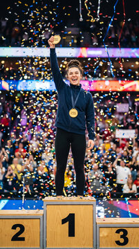Happy Female Champion Holding Gold Medal On Podium With Confetti Falling