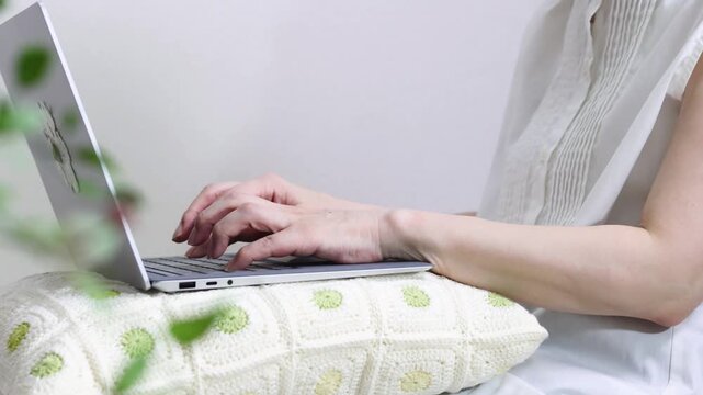 膝にノートパソコンを乗せて作業をする人　くつろいだ様子のイメージ