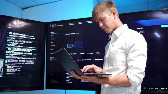 Concentrated software developer examining data displayed on a big screen in a contemporary technology workspace