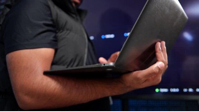 Detailed view of a software developer working on a laptop in a contemporary office environment with programming code visible on the screen
