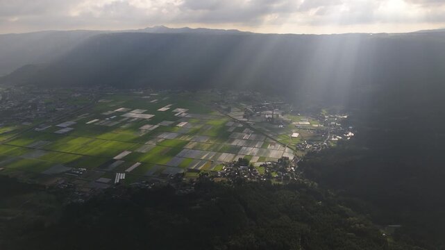 阿蘇の田園に降り注ぐ光の筋、カルデラ内の水田と集落を空撮（Aso Caldera Rice Fields with Sunbeams, Kumamoto Japan Aerial 4K）