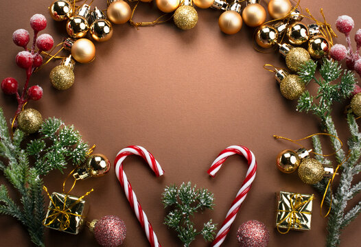 Christmas background with decorative candy canes, golden gift boxes, fir branch, balls, star and cones for tree decoraton. New Year winter holiday composition with decor and space for text, top view.