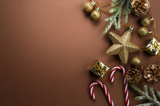 Christmas background with decorative candy canes, golden gift boxes, fir branch, balls, star and cones for tree decoraton. New Year winter holiday composition with decor and space for text, top view.