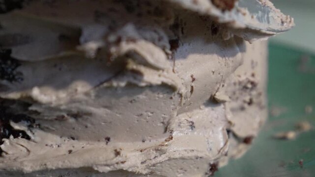 Cake frosting baking cake closeup professional pastry chef spreading creamy chocolate buttercream icing onto a dark chocolate sponge cake for dessert decoration