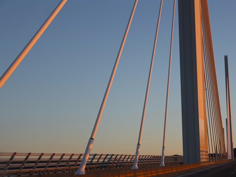 Vue rapproch&eacute;e d'haubans en acier fix&eacute;s &agrave; un haut pyl&ocirc;ne en b&eacute;ton arm&eacute;. Lignes blanches en acier servant &agrave; la fixation des tabliers de pont. Fond de ciel bleu en arri&egrave;re plan.