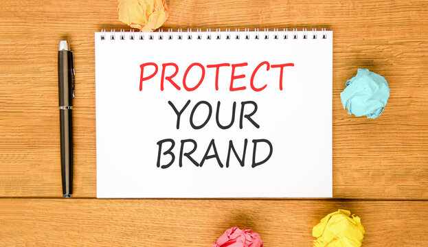 Protect your brand words symbol. Concept words Protect your brand on beautiful white note. Beautiful wooden background. Colored paper. Business and protect your brand concept. Copy space.