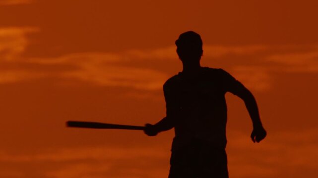 Youth practices baseball at sunset in a park