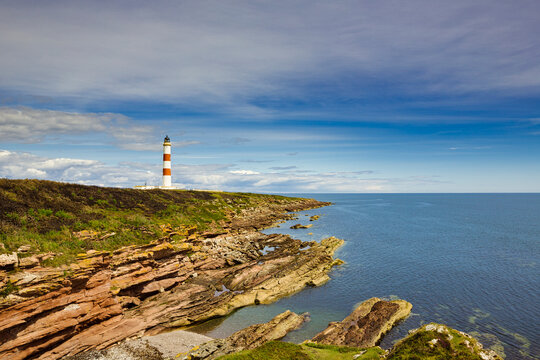 The rocky coastline of the Tarbat Ness peninsula with the lighthouse in the distance.