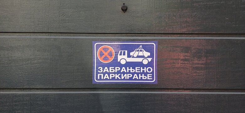 Blaues Parkverbotsschild mit kyrillischer Aufschrift und Abschleppwagen-Symbol an einem Garagentor