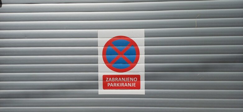 Parkverbotsschild-Aufkleber &bdquo;Zabranjeno Parkiranje&ldquo; auf einem grauen Rolltor