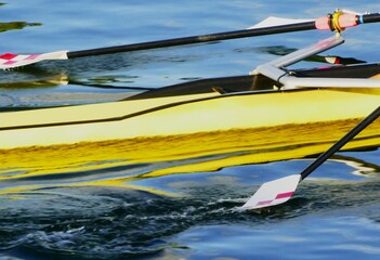 Yellow rowing boat with oar making a splash on the water in high speed motion, on the lake sports activities on the water background © moreidea