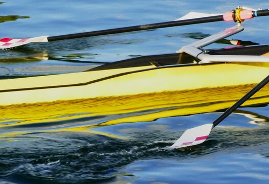 Yellow rowing boat with oar making a splash on the water in high speed motion, on the lake sports activities on the water background
