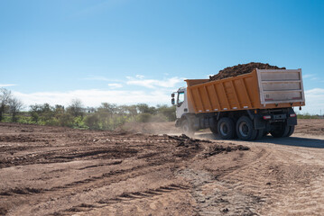 Dump truck loaded with soil driving at outdoor construction site © Matico