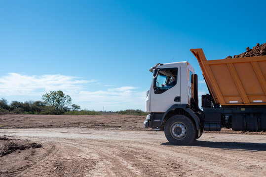 Dump truck loaded with soil driving at outdoor construction site