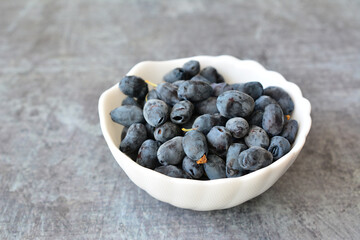 Bowl of Fresh Honeysuckle Berries on Gray Textured Surface, close up, copy space © Irina