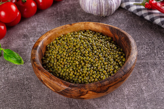 Green mung beans in rustic wooden bowl with cherry tomatoes and garlic