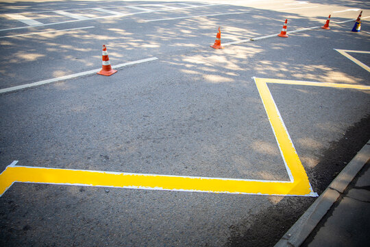 Road marking work is under way at a bus stop. The new yellow zigzag is drying along the kerb, fenced off by orange traffic cones