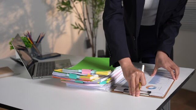 Businesswoman hands working in Stacks of paper files for searching and checking unfinished document achieves on folders papers at busy work desk office.	