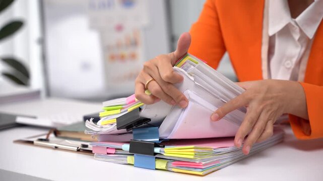 Businesswoman hands working in Stacks of paper files for searching and checking unfinished document achieves on folders papers at busy work desk office.	