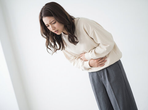 お腹の激痛に耐えかねて身体を折り曲げる女性